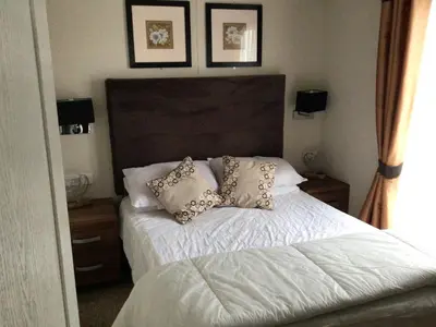 a bedroom with a bed with pillows on it at Newquay Haven caravan 42x14 with Ocean Views in New Quay