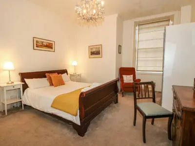 a bedroom with a bed and a chair and a chandelier at Caynham Court in Ludlow