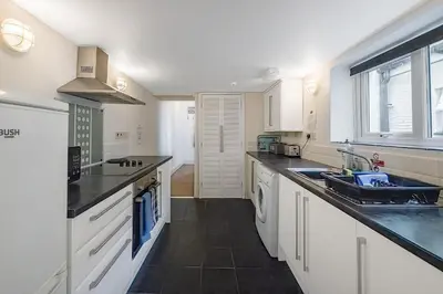 a kitchen with white cabinets and black counter tops at 2 Bed Ground Floor Beach Location in Aberdyfi