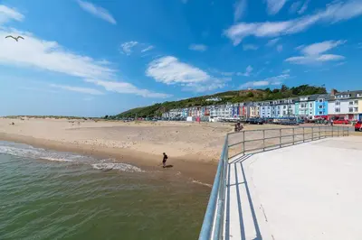 a person walking on the beach near the water at 2 Bed Ground Floor Beach Location in Aberdyfi