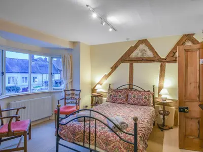 a bedroom with a bed and chairs and a window at Paul Pry in Ludlow