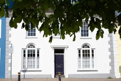 a white house with a black door and windows at Harbourside luxury house in Aberaeron