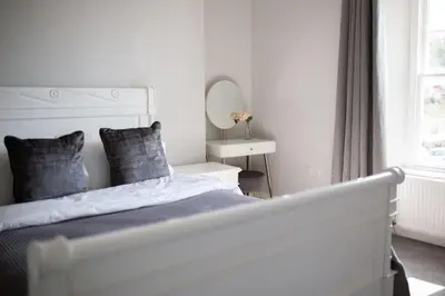 a white bedroom with a bed and a mirror at Harbourside luxury house in Aberaeron