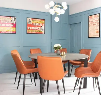 a dining room with a table and orange chairs at Harbourside luxury house in Aberaeron