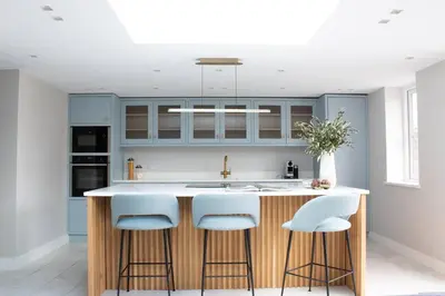 a kitchen with blue cabinets and a counter with stools at Harbourside luxury house in Aberaeron