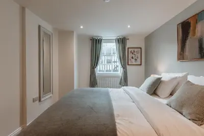 a bedroom with a large white bed and a window at 2 Bed Apartment Overlooking the Square Step Out to Shops & Dining in Shrewsbury