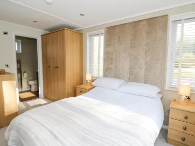 a bedroom with a large white bed and a bathroom at Seren Lodge in Builth Wells