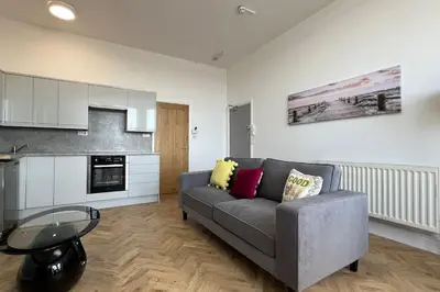 a living room with a gray couch and a table at Barmouth beach ground level in Barmouth