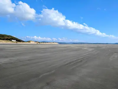 an empty beach with a blue sky and clouds at Cartref Guesthouse - Room 2 Ensuite in Aberdyfi