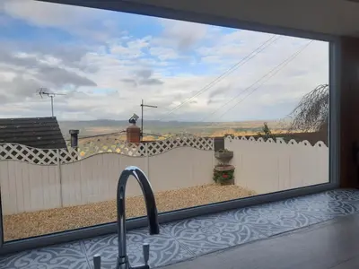 a kitchen window with a view of a fence at Jasmine Cottage in Shrewsbury