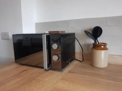 a microwave oven sitting on top of a kitchen floor at Jasmine Cottage in Shrewsbury