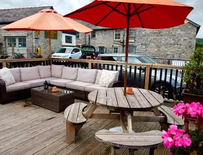 a patio with a couch and a table with an umbrella at Usk And Railway Inn in Sennybridge