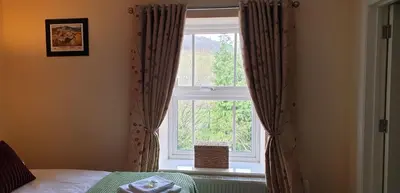 a bedroom with a window with curtains and a bed at Usk And Railway Inn in Sennybridge