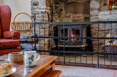 a living room with a stone fireplace with a table at 7 Bed in Talgarth oc-h30349 in Talgarth