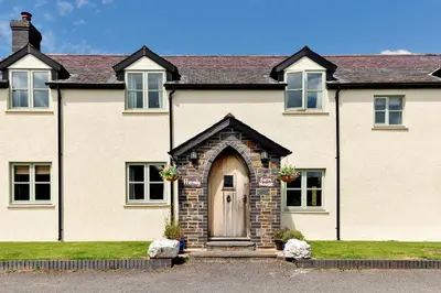 a large white house with a brown door at Finest Retreats - The Welsh Farmhouse in Aberystwyth