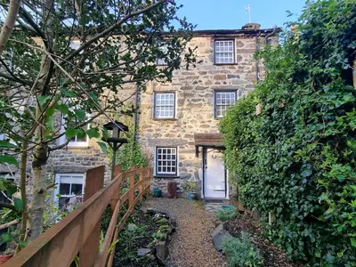 a stone house with a white door and a fence at River Cottage in Llanbedr