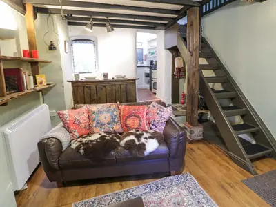 a living room with a couch and a staircase at River Cottage in Llanbedr