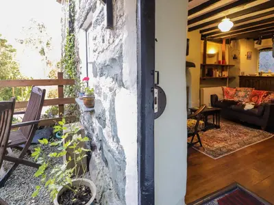 a door into a living room with a stone wall at River Cottage in Llanbedr