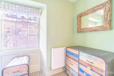 a room with a dresser and a mirror and a window at Seafront House in Aberdyfi