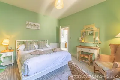 a bedroom with green walls and a bed and a chair at Seafront House in Aberdyfi
