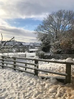 a wooden fence covered in snow in a field at Enchmarsh Farm Byre in Church Stretton
