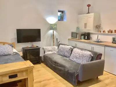a living room with a couch and a kitchen at Enchmarsh Farm Byre in Church Stretton