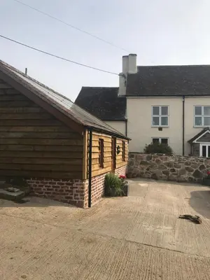a house with a garage and a stone wall at Enchmarsh Farm Byre in Church Stretton