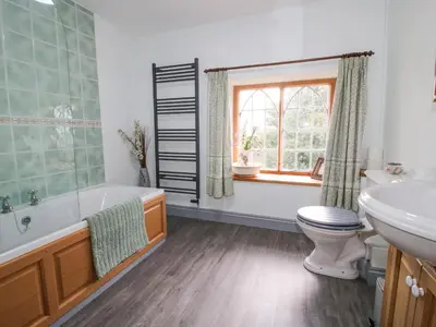a bathroom with a tub and a toilet and a sink at Rowan Cottage in Bishops Castle