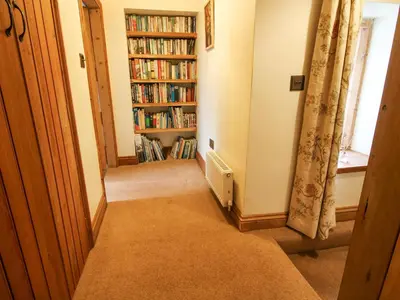a hallway with a book shelf filled with books at Rowan Cottage in Bishops Castle