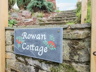 a sign for a rowan cottage on a stone wall at Rowan Cottage in Bishops Castle