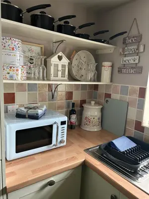 a kitchen with a microwave on top of a counter at Cosy riverside property in Aber-Brân