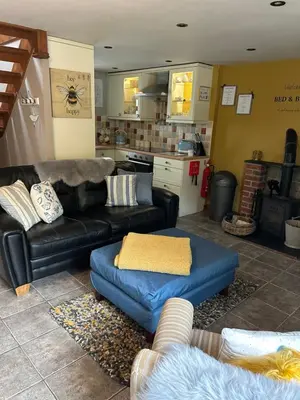 a living room with a black couch and a blue ottoman at Cosy riverside property in Aber-Brân