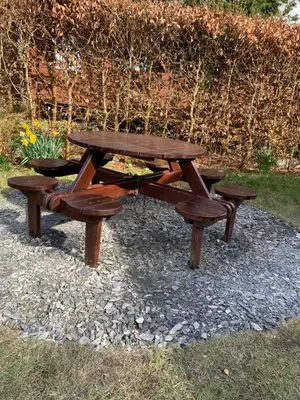 a wooden picnic table and benches in a park at Fernleys Place in Trawsfynydd