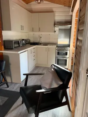 a kitchen with white cabinets and a black leather chair at Fernleys Place in Trawsfynydd