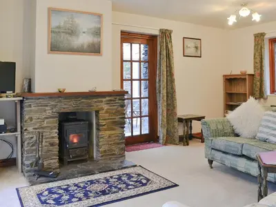 a living room with a stone fireplace and a couch at Erw Goed Hen Feudy in Arthog