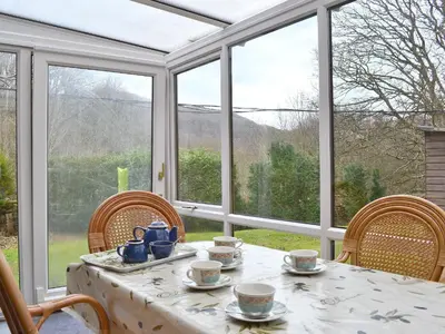 a dining room with a table and chairs and windows at Erw Goed Hen Feudy in Arthog