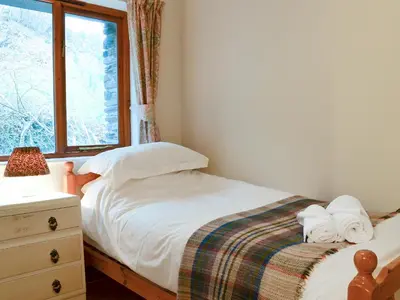 a small bedroom with a bed and a window at Erw Goed Hen Feudy in Arthog