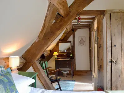 an attic room with a bedroom and a desk with a mirror at The Bothy-E2934 in Clun