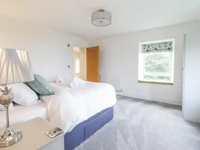 a white bedroom with a large bed and a table at Aelfor in Harlech