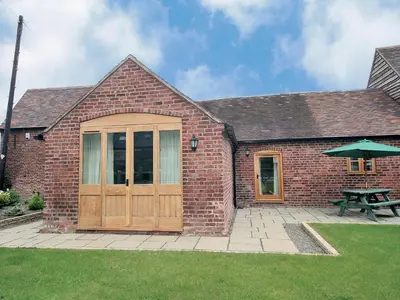 a brick building with a wooden door and a picnic table at Shippon Cottage - E4299A in Halston