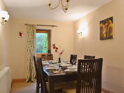 a dining room with a table and chairs and a window at Shippon Cottage - E4299A in Halston