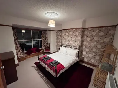 a bedroom with a bed with a red blanket at Glannant - 5 Bed & 4 Bathroom - Fairbourne, Barmouth, Mawddach Estuary in Arthog