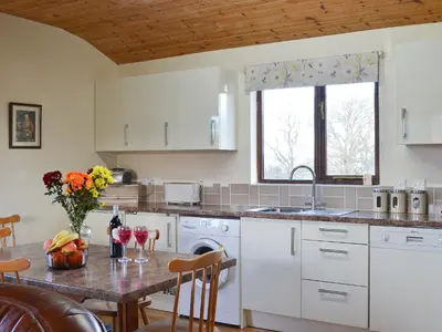 a kitchen with white cabinets and a table with flowers on it at Ithon Bank - Hw7478 in Penybont