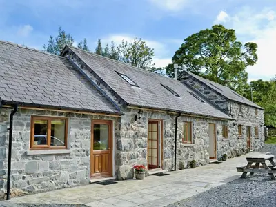 a stone cottage with a picnic table in front of it at Dol Afon - Hw7588 in Llanuwchllyn