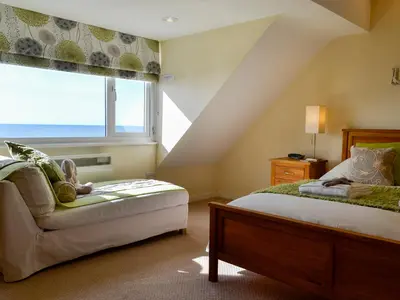 a bedroom with a bed and a chair and a window at Morlais - Hw7599 in Llanaber