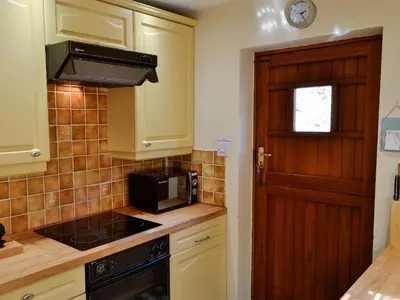 a kitchen with a stove top oven next to a door at Morlais - Hw7599 in Llanaber