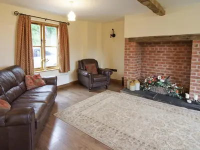 a living room with leather furniture and a brick fireplace at Cwm Corn Barn - Hw7662 in Mochdre
