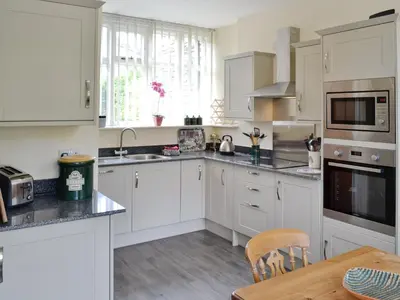 a kitchen with white cabinets and a wooden table at Station House - Hw7742 in Glyn-Dyfrdwy