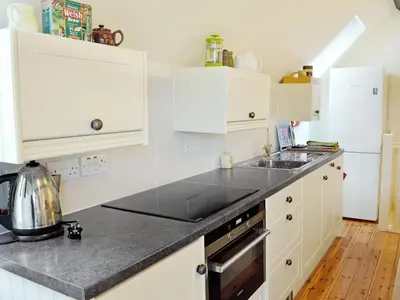 a kitchen with white cabinets and a black counter top at The Coach House - Hw7782 in Llanarmon Dyffryn-Ceiriog