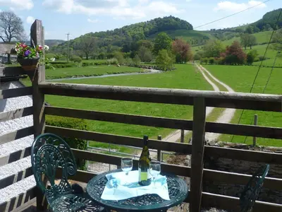 a table with a bottle of wine on top of a fence at The Coach House - Hw7782 in Llanarmon Dyffryn-Ceiriog